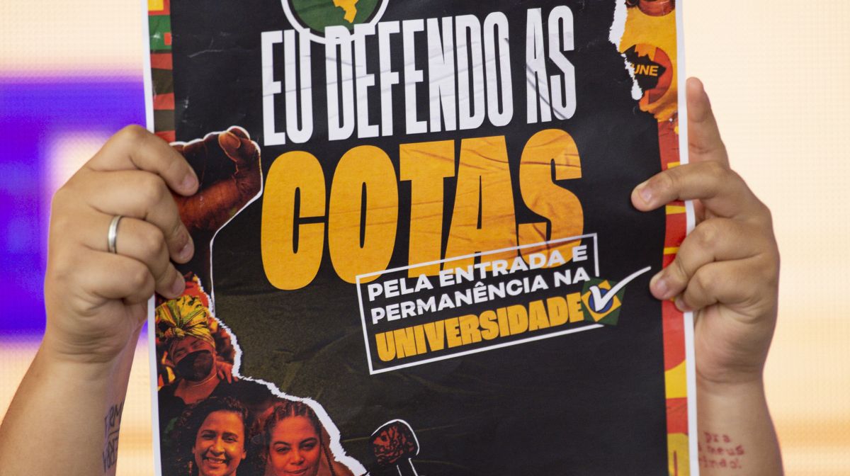 pessoa segurando cartaz sobre as cotas