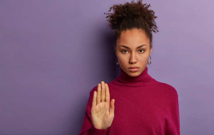 mulher fazendo sinal de "pare" com a mão