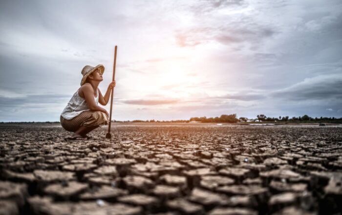 mulher sobre solo seco observando as mudanças climáticas