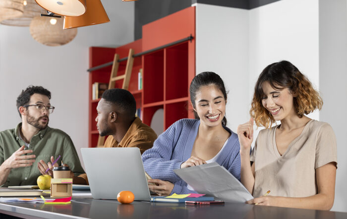 jovens sentados em grupo estudando e trabalhando com computadores, canetas, papéis e livros