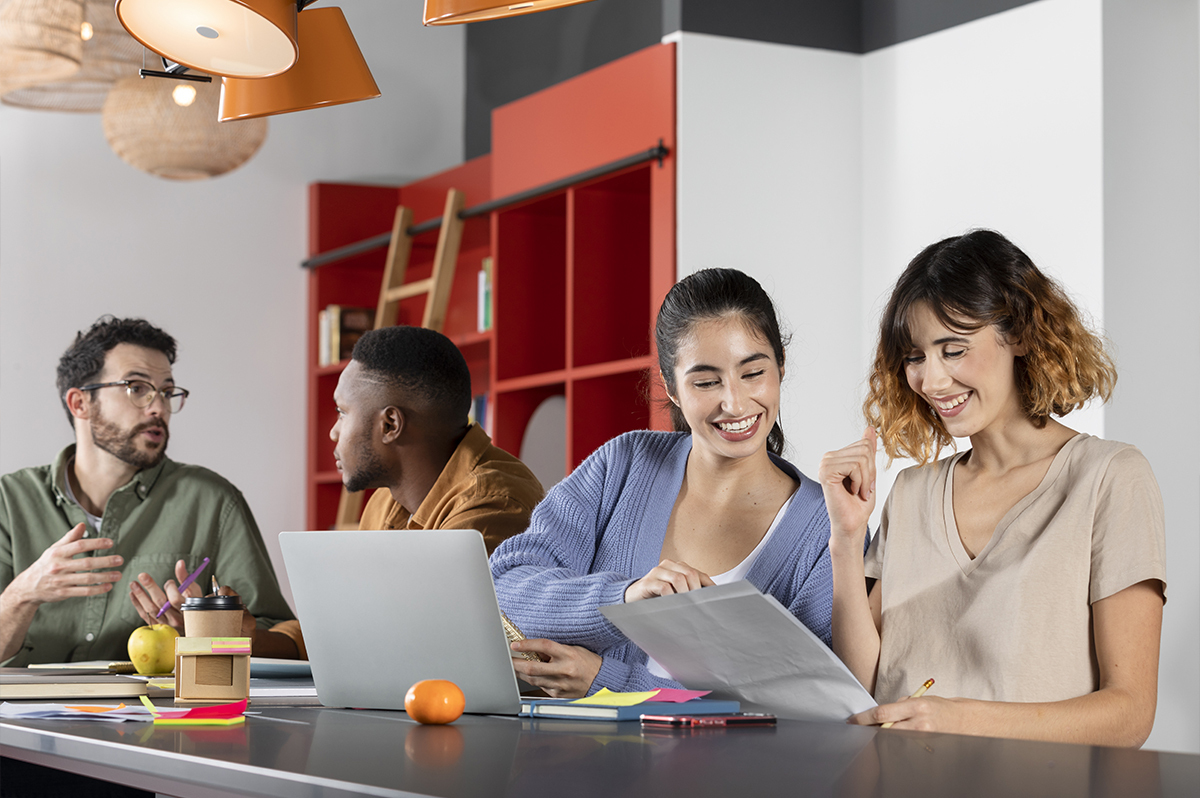 jovens sentados em grupo estudando e trabalhando com computadores, canetas, papéis e livros